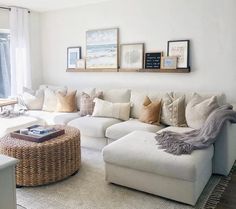 a living room with white couches and pictures on the wall above them, along with a coffee table