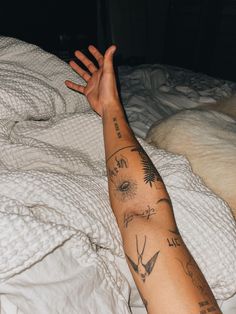 a person with tattoos on their arm laying in bed