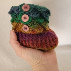 there is a hand holding three small crocheted purses with buttons on them