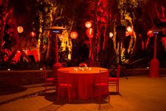 an outdoor event with red lighting and tables set up for a formal function at night