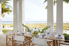 an outdoor dining area with table, chairs and vases in front of the ocean