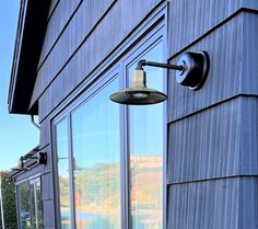 a lamp on the side of a building next to a window with water in it