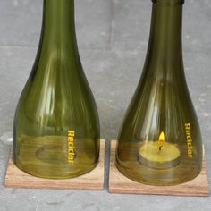 two green vases sitting on top of a wooden stand with a lit candle in them