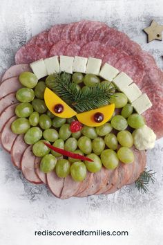 a platter with grapes, meat and cheese in the shape of a face