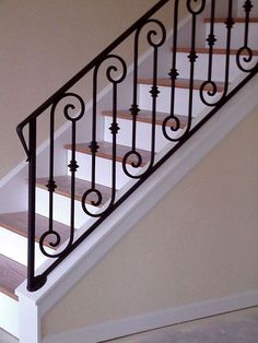 a stair case with wrought iron handrails and wood flooring