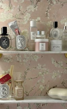 the shelves are filled with different types of perfumes and personal care products in front of a floral wallpaper