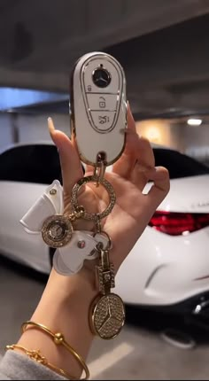 a person holding up a cell phone in front of a car with keys attached to it