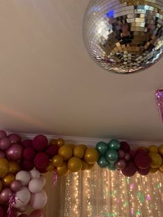 there is a disco ball hanging from the ceiling and balloons on the wall behind it