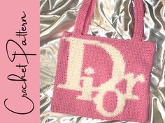 a pink crocheted bag with the letter d on it's front and bottom