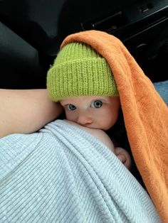 a baby wrapped up in a blanket and wearing a green knitted hat on top of it's head