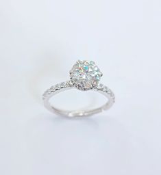 a white gold ring with an oval cut diamond in the center and pave set shoulders