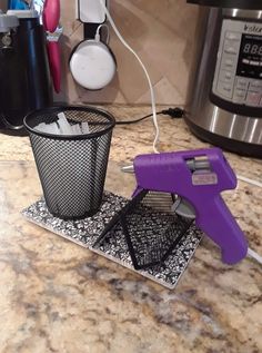 a kitchen counter with a purple and black object on it's stand next to an electric pressure cooker