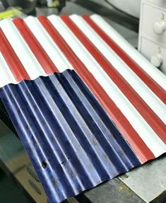 an american flag painted on the side of a metal sheet in a factory area with other items nearby