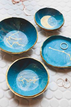 three blue bowls with gold designs on them and two wedding rings in the middle one