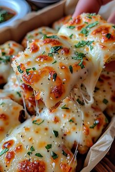 a close up of a person holding a piece of pizza with cheese and herbs on it