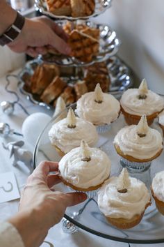 a person reaching for some cupcakes on a plate