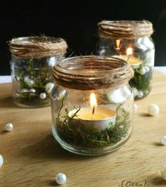 three mason jars filled with moss and lit candles