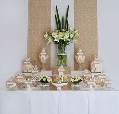 a table topped with vases filled with white flowers and candies on top of it