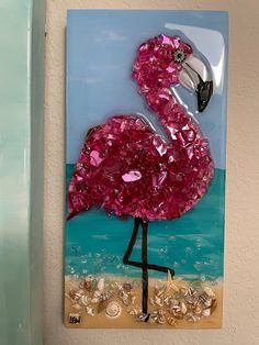 a pink flamingo standing on top of a sandy beach