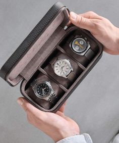 a person holding an open case with three watches in it