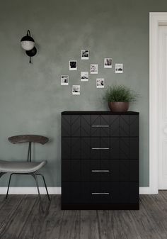 an empty room with a chair, plant and pictures on the wall