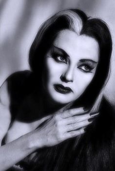 a black and white photo of a woman with makeup on her face, holding her hands to her chest