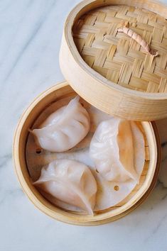 three dumplings in a bamboo container on a marble surface