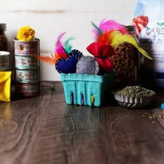 there are many items on the table and one is in a blue basket with feathers