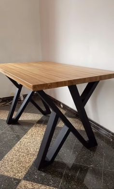 a wooden table sitting on top of a tiled floor next to a white wall in an empty room