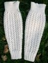 two white knitted gloves laying in the grass