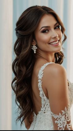 a woman with long hair wearing a white dress and smiling at the camera while standing in front of a curtain