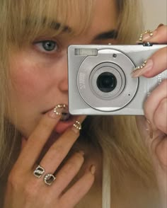 a woman taking a selfie with her camera in front of her face and nails on