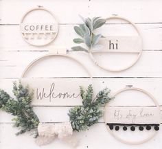 three embroidery hoop wreaths with the words welcome and coffee written on them, hanging on a white wooden wall