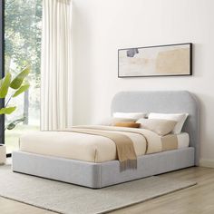 a bed sitting on top of a wooden floor next to a window