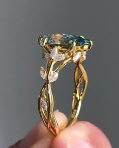 a close up of a person's hand holding a ring with an aqua and white diamond