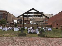 an outdoor venue with tables and chairs set up for a formal function in front of a brick building