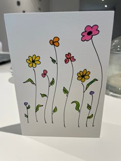 a card with flowers painted on it sitting on a table