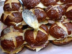 a tray filled with hot dogs covered in cheese and sauce, next to a spoon