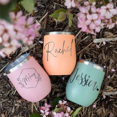 three personalized wine tumblers sitting on the ground next to some pink and purple flowers