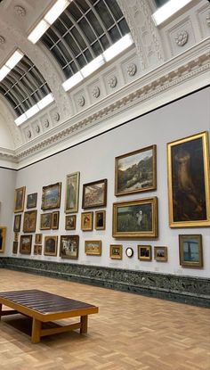 a large room with many paintings on the wall and wooden benches in front of it