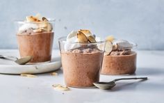 three desserts in small glass bowls with spoons