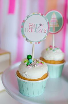 two cupcakes sitting on top of a plate with white frosting and decorations