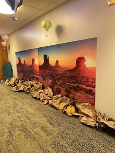 an empty room with paintings on the wall and balloons floating in the air above it