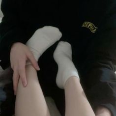 a person with white socks and black shirt holding their leg up to the camera while sitting on a couch