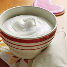 a bowl of yogurt sitting on top of a table next to a napkin