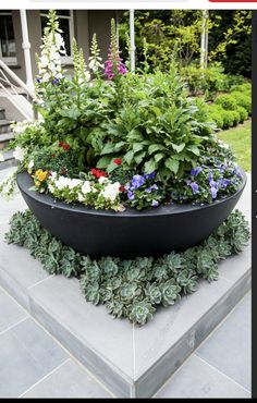 a large planter filled with lots of flowers sitting on top of a cement slab