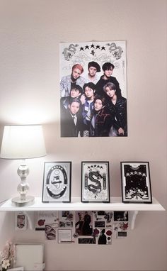 a white shelf topped with pictures next to a lamp