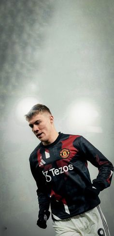 a man standing in front of a soccer ball with his hands on his hips while wearing a black and red shirt