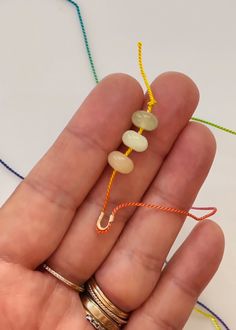 a person is holding some beads in their hand and there are other beads on the string