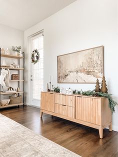 a living room filled with furniture and christmas decorations on top of a wooden shelf next to a window